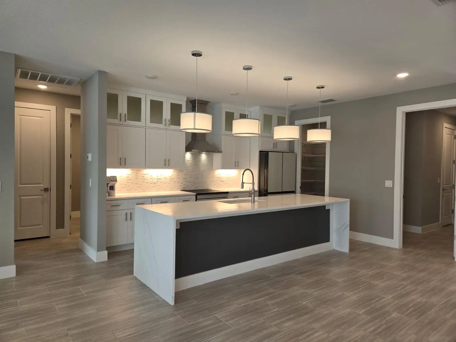 Open-concept kitchen with a white waterfall-edge island and pendant lights