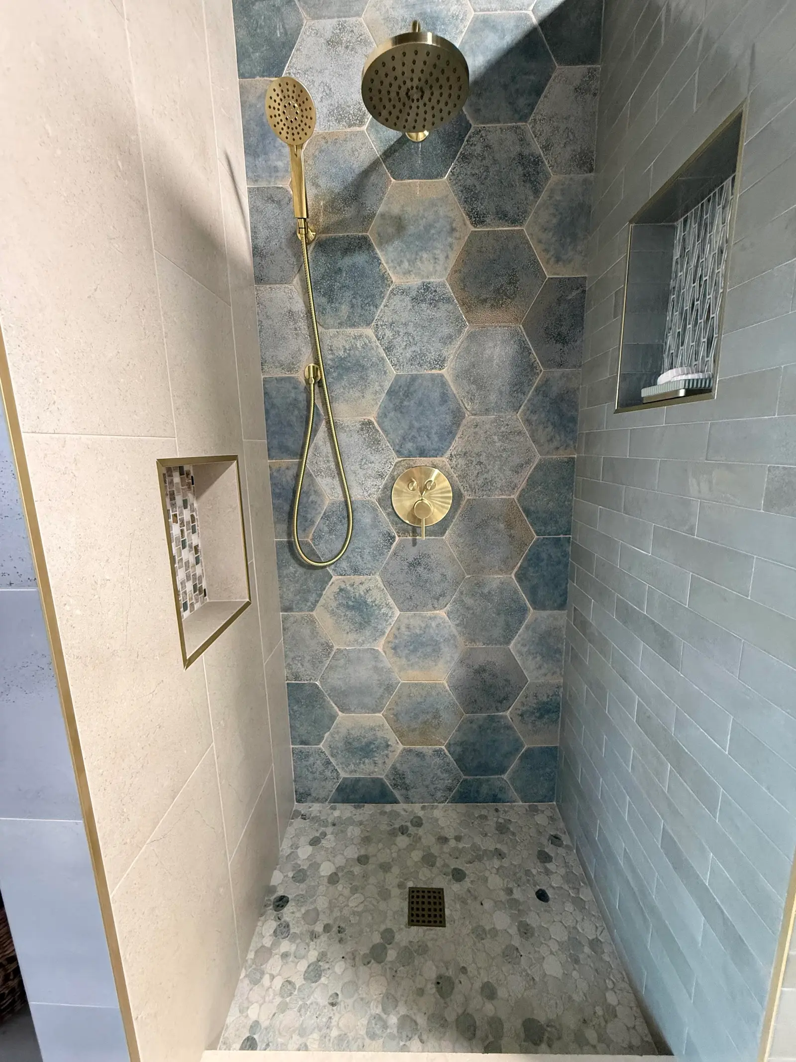 Shower with blue hexagon tile accent wall and brushed brass fixtures