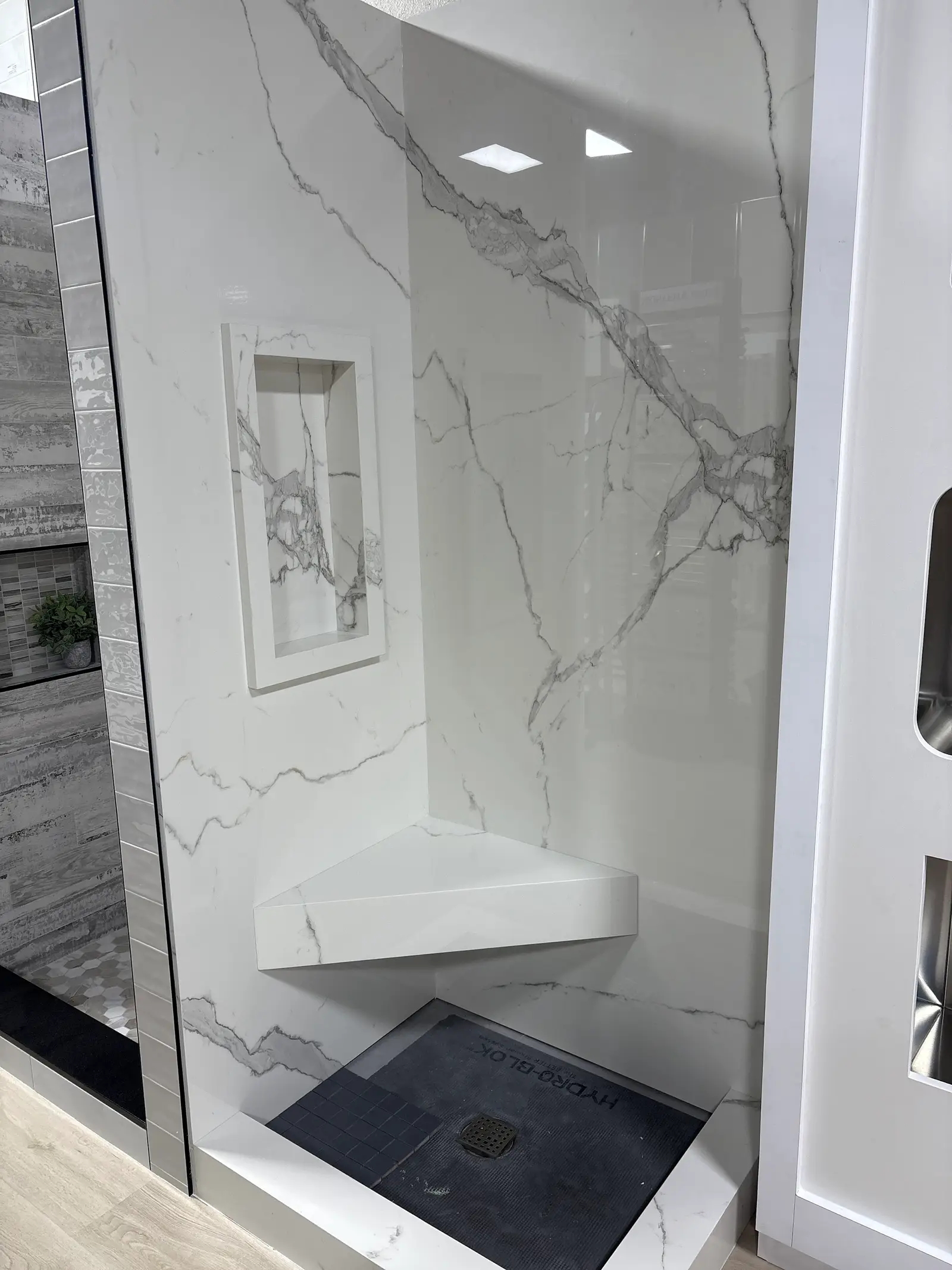 Porcelain slab shower with a corner bench and black floor tile