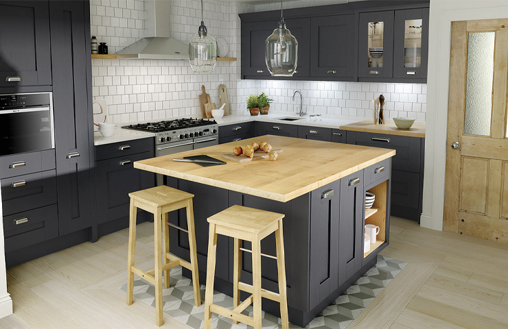 Modern kitchen with dark cabinets, a wooden island with stools, stainless steel appliances, and white tiled backsplash. Geometric patterned flooring surrounds the island.