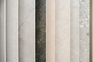 Vertical array of stone slabs in varying shades of gray, beige, and black, displaying diverse textures and patterns—perfect inspiration for choosing the best countertops for Florida homes.