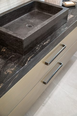 Rectangular black stone sink on a dark marble kitchen countertop with two metal drawer handles below—perfect for those looking to choose a countertop edge that complements modern design.