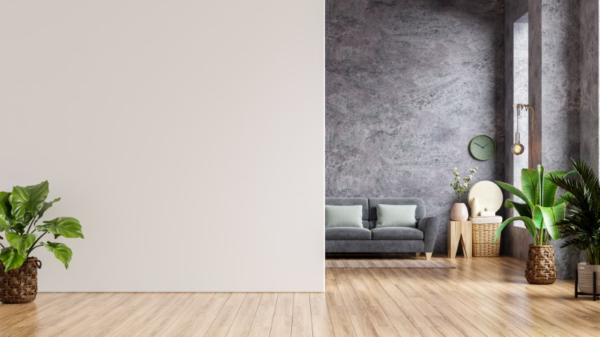 A modern luxury living room featuring a gray sofa, green cushions, indoor plants, wooden floor, and a textured stone accent wall adorned with a clock and decorative items.